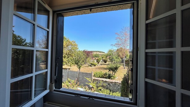 A window with a view of a garden and a stone wall. - VILLA NORA: HOUSE WITH A SWIMMING POOL IN DEMANGE-AUX-EAUX (DEMANGE BAUDIGNECOURT)
