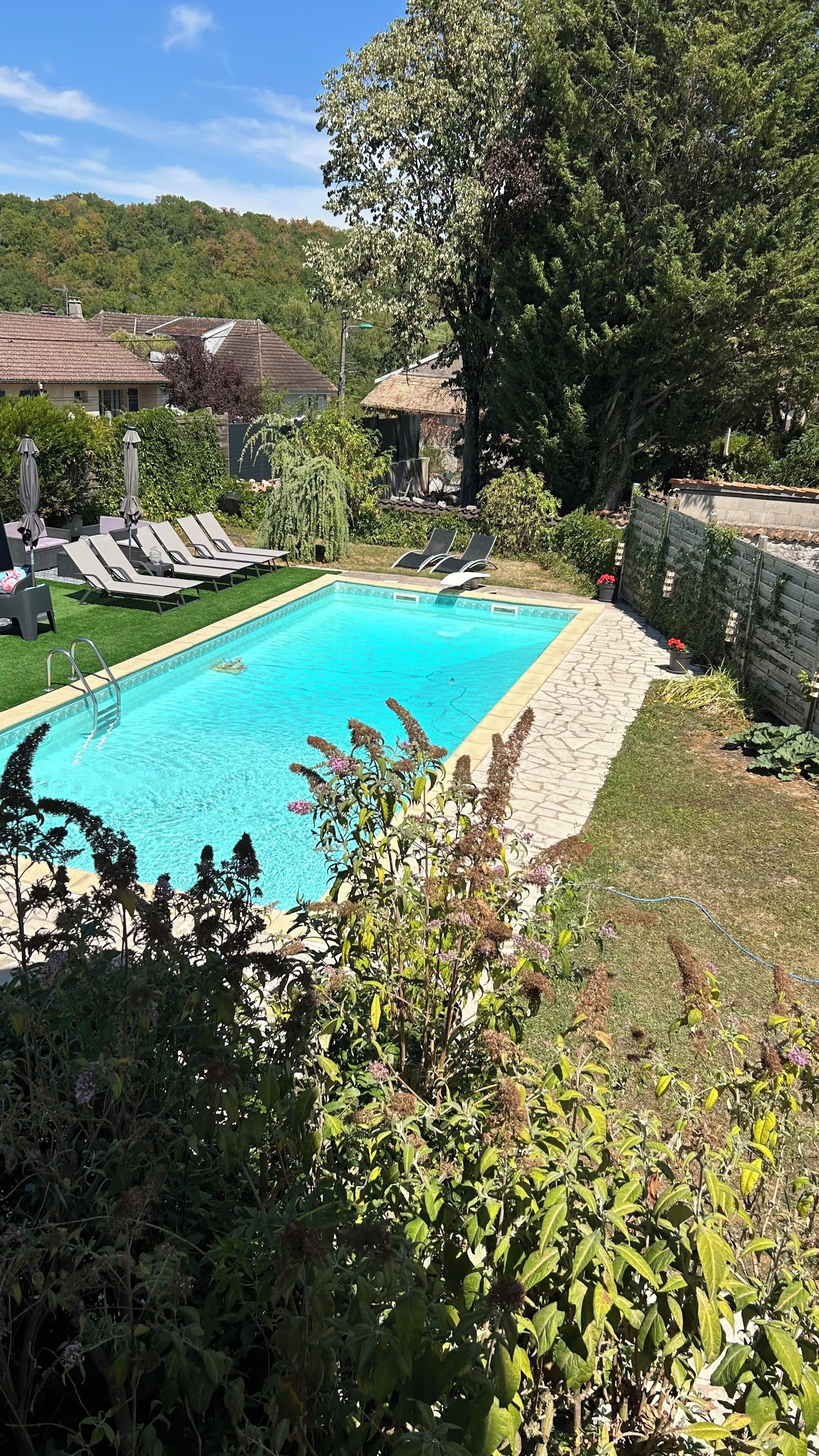 Una piscina con sillas de descanso y un muro de piedra.