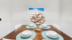 A dining area with a wooden table, white chairs, and a centerpiece of wooden fish sculptures. - Runaway Beach Club Disney Retreat (Kissimmee)