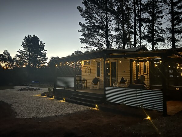 A cabin with a porch, outdoor seating, and string lights.