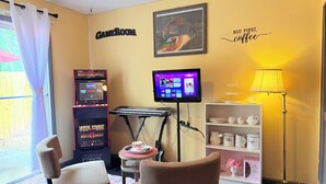 Une pièce équipée d’une console de jeux, d’un téléviseur, d’un coin café et d’une bibliothèque.
