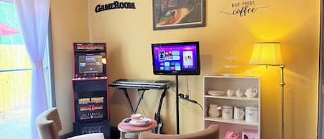 Une pièce équipée d’une console de jeux, d’un téléviseur, d’un coin café et d’une bibliothèque.