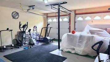A gym with exercise equipment, a basketball, and a covered item.