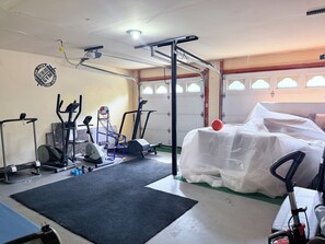 A gym with exercise equipment, a basketball, and a covered item. - Large 3BR Home • Atlanta Metro • Fenced Yard • Arcade • Long & Short Stays (Duluth)
