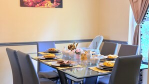 Un coin repas avec une table en verre, six chaises et un tableau accroché au mur.