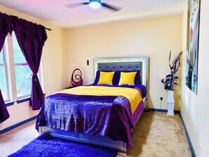 A bedroom with a bed, curtains, a vase with flowers, and a ceiling fan. - Large 3BR Home • Atlanta Metro • Fenced Yard • Arcade • Long & Short Stays (Duluth)