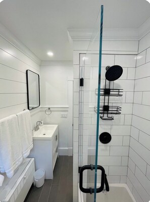 Ein modernes Badezimmer mit Duschkabine aus Glas, einem weißen Waschbecken und einem Spiegel.
