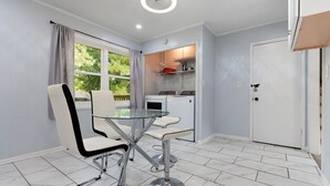 A compact kitchen with a glass-top table and chairs, a white door, and a window with curtains. - Perfect 3-bedroom house with AC in welcoming Birmingham. (Birmingham)