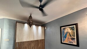 Un pasillo con ventilador de techo, una puerta de madera y una obra enmarcada en la pared.