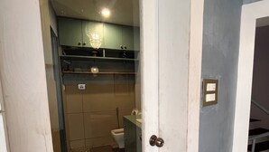Un pasillo estrecho que conduce a un baño con inodoro, lavabo y armario.