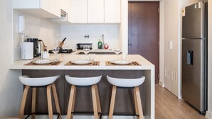 A modern kitchen with a central island, bar stools, a refrigerator, and a microwave. - Sight 1601 · Luxe King Bed 1BR •Rooftop Pool, Gym, AC & Parking (Lima)