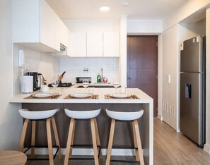 Eine moderne Küche mit einer zentralen Kochinsel, Barhocker, einem Kühlschrank und einer Mikrowelle.