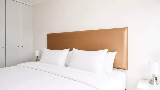 A hotel room with a bed, a nightstand, and a wardrobe. - Sight 1601 · Luxe King Bed 1BR •Rooftop Pool, Gym, AC & Parking (Lima)