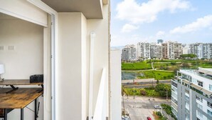 A balcony with a view of a cityscape, a table, and a chair. - Sight 1601 · Luxe King Bed 1BR •Rooftop Pool, Gym, AC & Parking (Lima)
