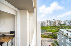 Ein Balkon mit Blick auf eine Stadtlandschaft, einem Tisch und einem Stuhl.