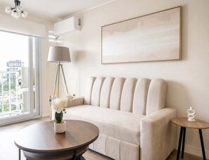 A modern living room with a sofa, a round table, a lamp, and a painting on the wall. - Sight 1601 · Luxe King Bed 1BR •Rooftop Pool, Gym, AC & Parking (Lima)