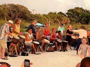 Un groupe de personnes joue de la batterie sur une plage de sable.