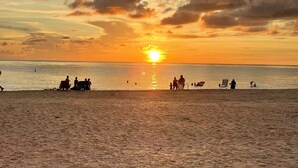 A beach scene with the sun setting over the water, silhouettes of people and beach chairs. - Charming 1-bedroom studio near Venice Beach (Venice)