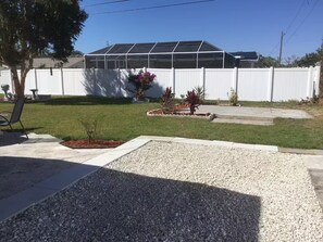 A residential backyard with a white fence, a small garden area with plants, and a patio with a chair. - Charming 1-bedroom studio near Venice Beach (Venice)