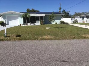 A residential property with a garage, solar panels, a well-maintained lawn, and a clear sky. - Charming 1-bedroom studio near Venice Beach (Venice)
