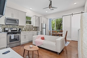 A modern kitchen with white cabinets, a microwave, stove, and a dining area with a table and chairs.