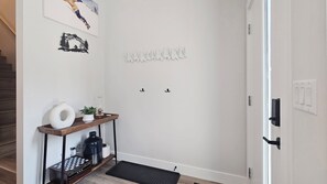 A hallway with a wooden console table, a black mat, and a door with a handle. - Newest Nordix Townhome Premium ski in/out Location (Panorama)