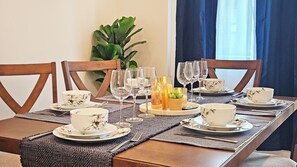 Una mesa de comedor con vajilla de flores, tazas, platones y diferentes vasos.