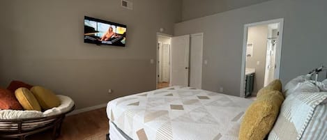 Une chambre à coucher avec un lit, un téléviseur, un ventilateur de plafond et une porte.