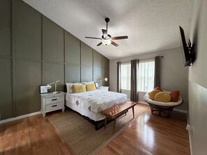 Une chambre à coucher avec un lit, une table de chevet, une lampe et un ventilateur de plafond.