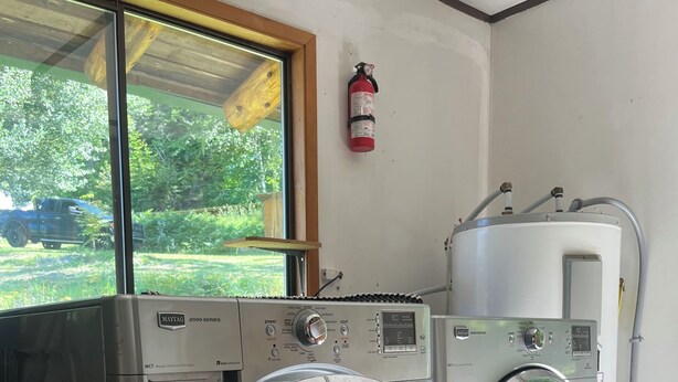 A laundry room with two Maytag 2000 series front-loading washers and a water heater.