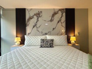 A hotel room with a large bed, two bedside lamps, a marble-patterned wall, and a modern design. - Cozy 1 bedroom apartment with AC in San Salvador (San Salvador)