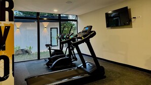 A gym with treadmills and an elliptical machine, a TV mounted on the wall, and a large window providing a view of the outdoors. - Cozy 1 bedroom apartment with AC in San Salvador (San Salvador)