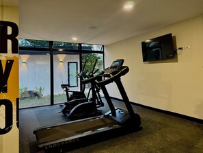 A gym with treadmills and an elliptical machine, a TV mounted on the wall, and a large window providing a view of the outdoors. - Cozy 1 bedroom apartment with AC in San Salvador (San Salvador)