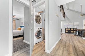 Un apartamento moderno con lavandería, una cama y zona de comedor.