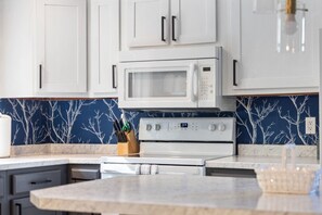 A kitchen with white cabinets, a microwave, and a stove.