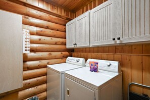 A laundry room with wooden walls and cabinets, two washing machines, and a detergent packet.