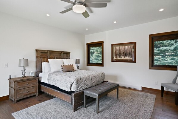 A bedroom with a bed, bedside tables, a bench, and a ceiling fan.