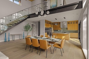 Eine moderne Küche mit Holzschränken, einem Edelstahlkühlschrank und einem Essbereich mit einem Tisch für sechs Personen.