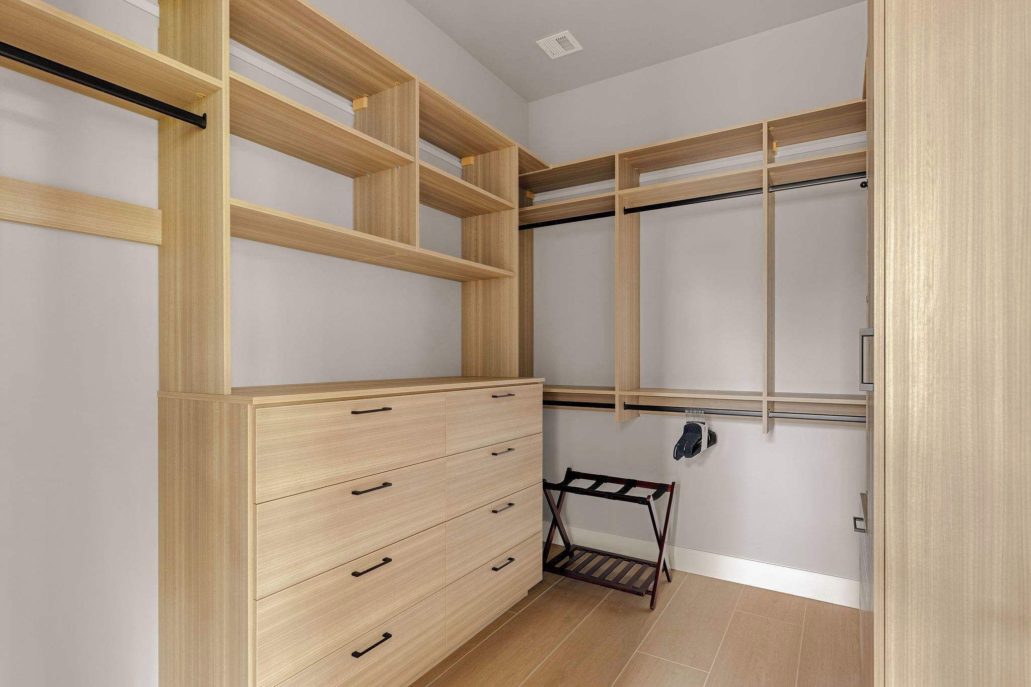 Un vestidor con estanterías de madera, cómoda empotrada y zapatero.