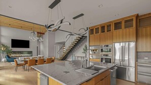 Uma cozinha moderna com uma ilha central, eletrodomésticos de aço inoxidável e armários de madeira.