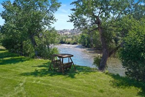 A riverside view with a wooden gazebo and lush greenery. - Boulder River Cabin | Riverfront Views | Sleeps 4 (Big Timber)