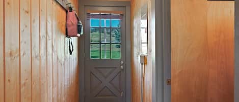 A wooden interior hallway with a door, a window, and a coat rack.