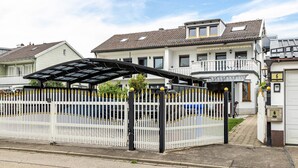 Una zona residencial con acceso por portón, un garaje cubierto y casas con techos de tejas.