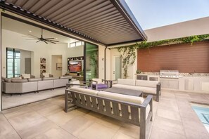 Ein moderner Außenbereich mit einer Couch, einem Esstisch und einem Grill.