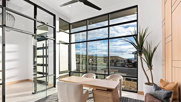 A modern office space with a large desk, chairs, and a view through expansive glass windows. - Luxury Mansion w/ Private Pool & Spa l Mini Golf (Hurricane)