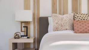 A neatly made bed with a white comforter and patterned pillows, a bedside table with a lamp, and a wooden headboard. - Luxury Mansion w/ Private Pool & Spa l Mini Golf (Hurricane)