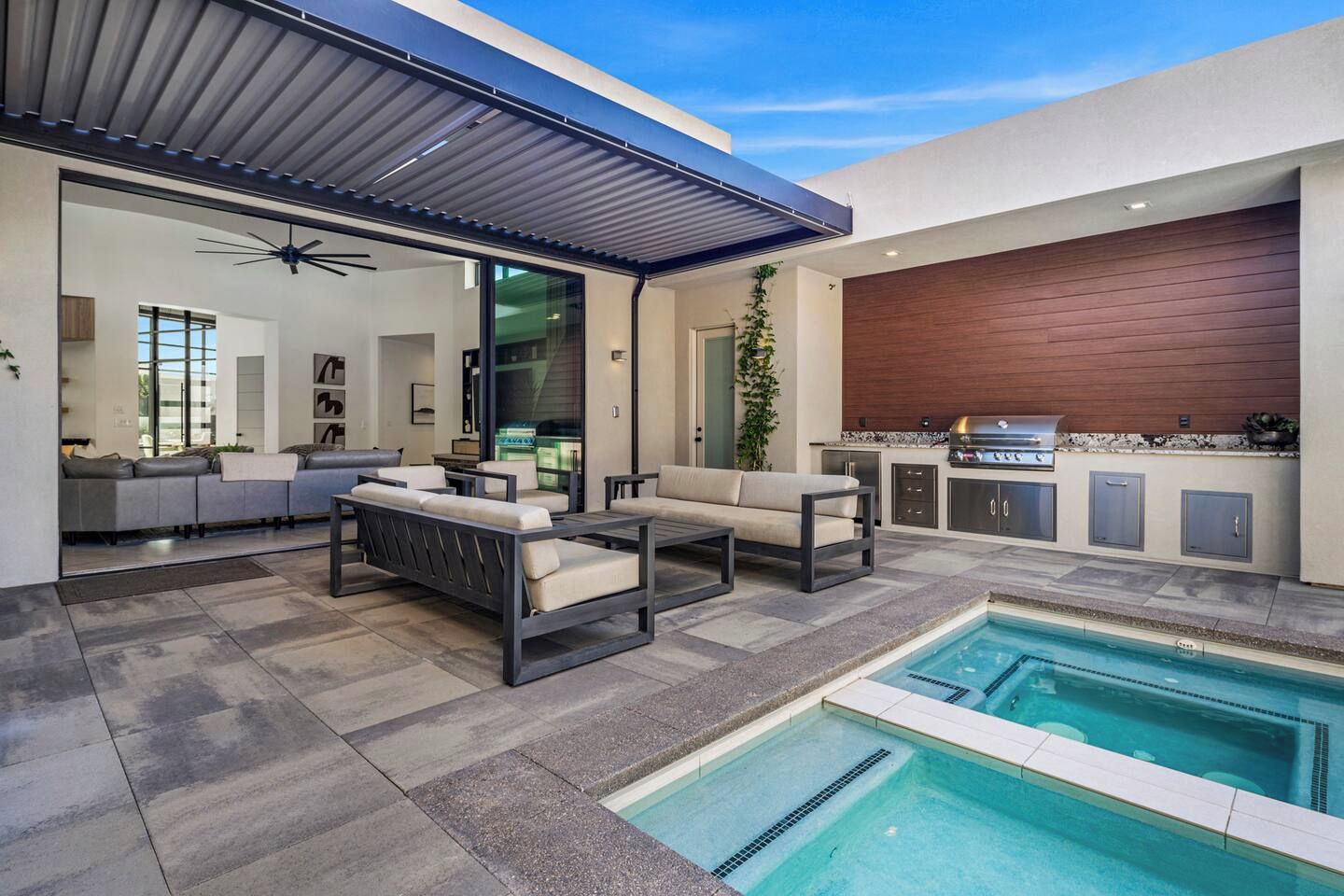 A modern outdoor living space with a pool, seating area, and a barbecue station.