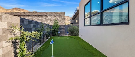 Un edificio moderno con césped cuidado y muros de piedra.