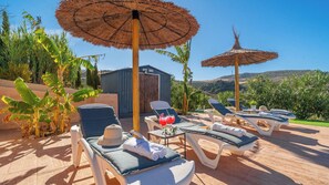 A sunlit outdoor lounge area with lounge chairs, a table, and a drink. - Casa Rural de Piedra Valle de Abdalajís by Ruralidays (Málaga)
