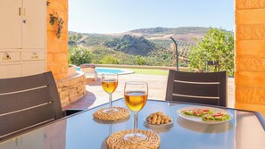 Un espace extérieur aménagé pour prendre les repas, avec une table, des chaises et une vue sur les collines.
